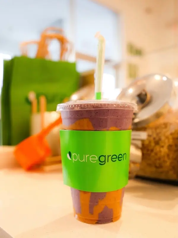 Purple smoothie in a Pure Green cup on the store counter.
