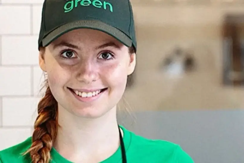 Smiling Pure Green crew member in a green cap and t-shirt.