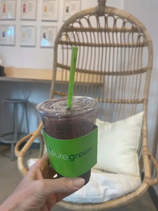 A Pure Green smoothie held up beside the hanging rattan chair at Dean Street