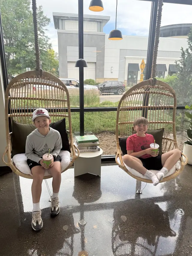 Kids relaxing in the rattan hanging chairs outside Pure Green Fort Collins